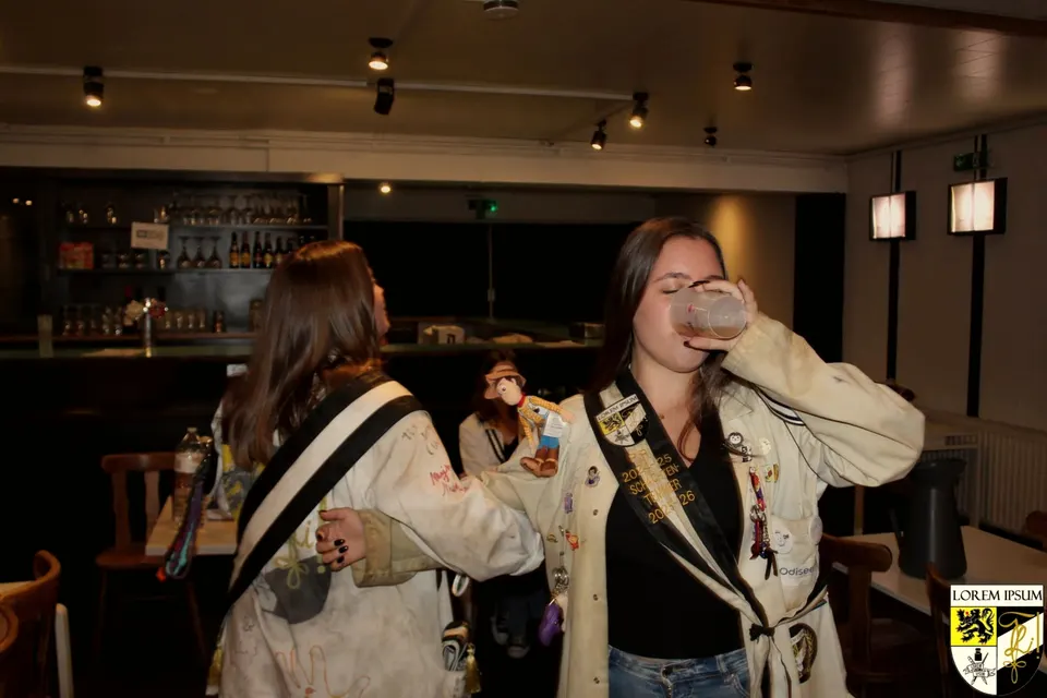 Twee leden met lint en clubvest drinken een glas in het café